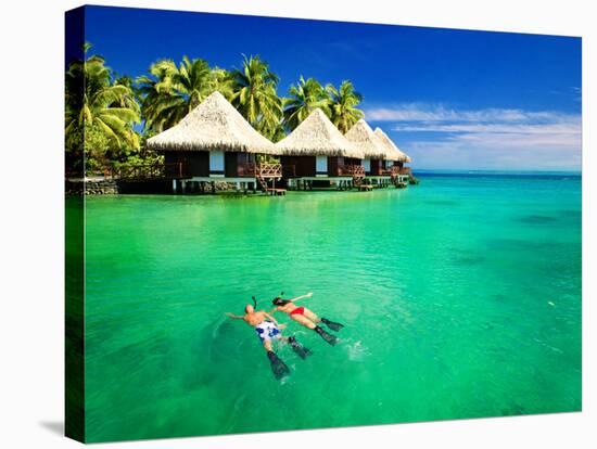 Couple Snorkling in Tropical Lagoon with over Water Bungalows-Martin Valigursky-Stretched Canvas