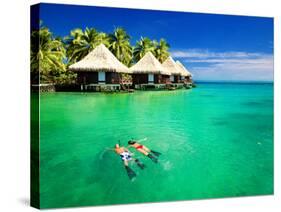 Couple Snorkling in Tropical Lagoon with over Water Bungalows-Martin Valigursky-Stretched Canvas