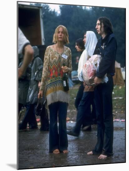 Couple Standing Barefoot on a Road Holding a Bundle and Wine Bottle, Woodstock Music and Art Fair-John Dominis-Mounted Premium Photographic Print