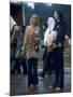 Couple Standing Barefoot on a Road Holding a Bundle and Wine Bottle, Woodstock Music and Art Fair-John Dominis-Mounted Photographic Print