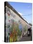 Couple Walking Along the East Side Gallery Berlin Wall Mural, Berlin, Germany, Europe-Simon Montgomery-Stretched Canvas