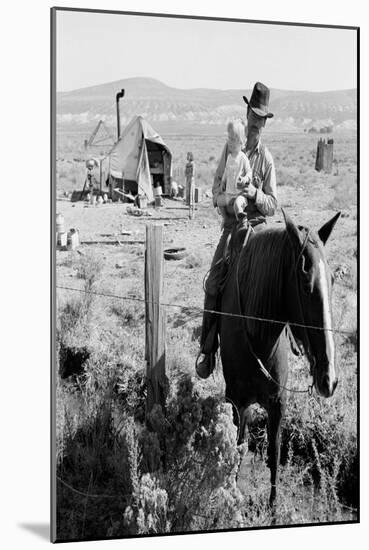 Cowboy Holds His Baby While Riding a Horse-Dorothea Lange-Mounted Art Print