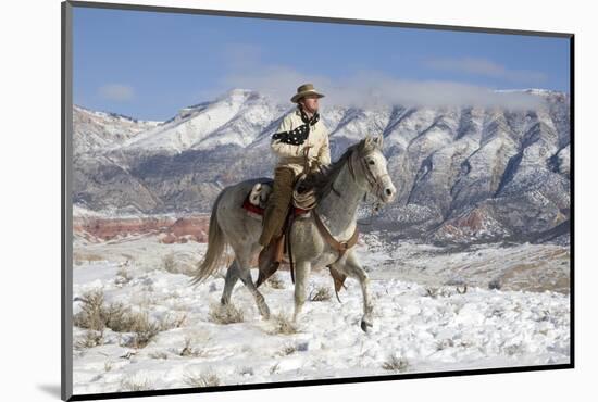 Cowboy On Grey Quarter Horse Trotting In The Snow At Flitner Ranch, Shell, Wyoming-Carol Walker-Mounted Photographic Print
