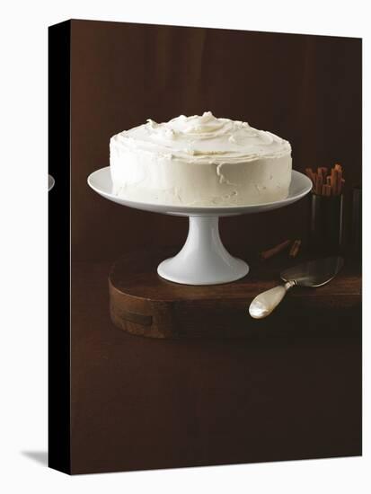 Cream Layer Cake on a Cake Stand Next to a Pot of Cinnamon Sticks - Conde Nast Collection-null-Stretched Canvas