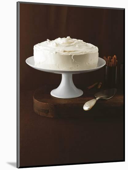 Cream Layer Cake on a Cake Stand Next to a Pot of Cinnamon Sticks - Conde Nast Collection-null-Mounted Photographic Print