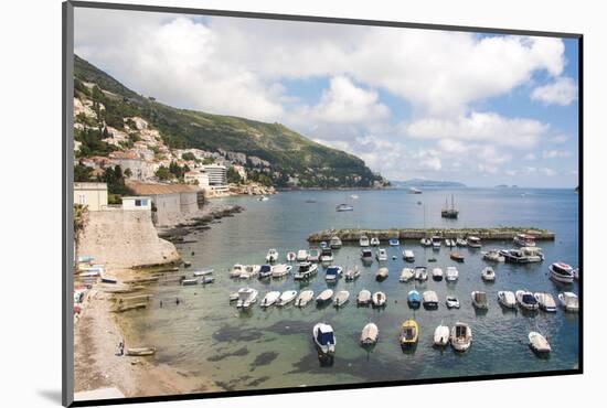 Croatia, Dubrovnik. View of marina and coastline from old city wall. Fisherman stands on shore.-Trish Drury-Mounted Photographic Print