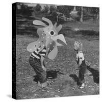 Curious Girl Looking at a Toy Chicken Head Toy by Charles Eames-Allan Grant-Stretched Canvas