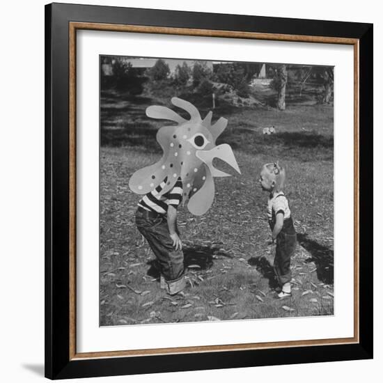 Curious Girl Looking at a Toy Chicken Head Toy by Charles Eames-Allan Grant-Framed Photographic Print