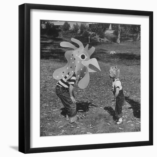 Curious Girl Looking at a Toy Chicken Head Toy by Charles Eames-Allan Grant-Framed Photographic Print