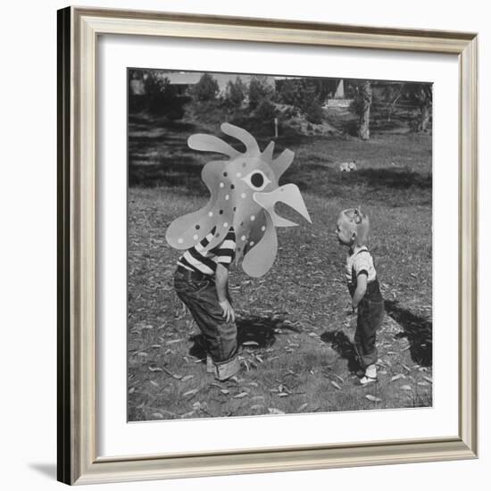 Curious Girl Looking at a Toy Chicken Head Toy by Charles Eames-Allan Grant-Framed Photographic Print