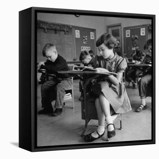 Cute Little Girl Busily at Work, Sitting in a Desk Chair in a Schoolroom, Other Pupils at Work Too-Gordon Parks-Framed Stretched Canvas
