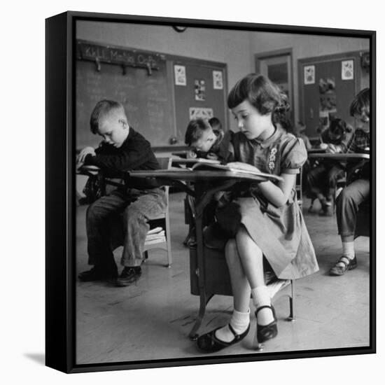 Cute Little Girl Busily at Work, Sitting in a Desk Chair in a Schoolroom, Other Pupils at Work Too-Gordon Parks-Framed Stretched Canvas