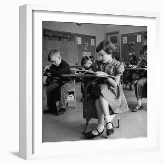 Cute Little Girl Busily at Work, Sitting in a Desk Chair in a Schoolroom, Other Pupils at Work Too-Gordon Parks-Framed Photographic Print