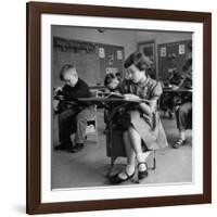 Cute Little Girl Busily at Work, Sitting in a Desk Chair in a Schoolroom, Other Pupils at Work Too-Gordon Parks-Framed Photographic Print