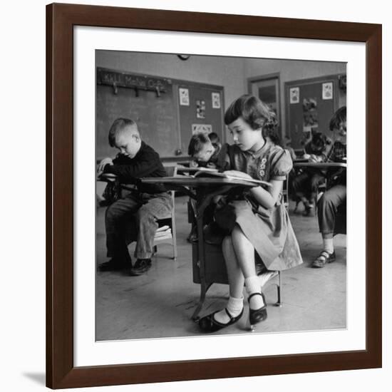 Cute Little Girl Busily at Work, Sitting in a Desk Chair in a Schoolroom, Other Pupils at Work Too-Gordon Parks-Framed Photographic Print