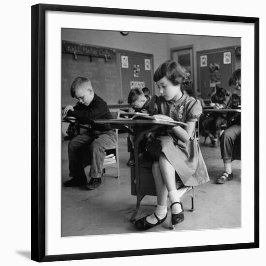 Cute Little Girl Busily at Work, Sitting in a Desk Chair in a Schoolroom, Other Pupils at Work Too-Gordon Parks-Framed Photographic Print