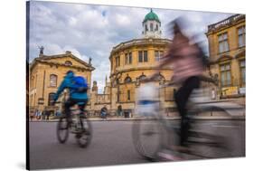 Cyclists Passing the Sheldonian Theatre, Oxford, Oxfordshire, England, United Kingdom, Europe-John Alexander-Stretched Canvas