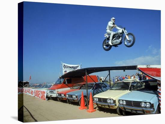 Daredevil Motorcyclist Evil Knievel in Mid Jump over a Row of Cars-Ralph Crane-Stretched Canvas