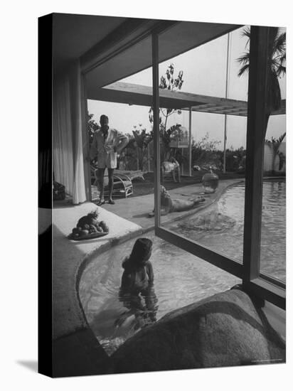 Designer Raymond Loewy Relaxing by Swimming Pool Which Runs from Outdoors Into Living Room-Peter Stackpole-Stretched Canvas