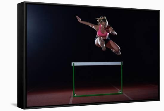 Determined Young Woman Athlete Jumping over a Hurdles-dotshock-Framed Stretched Canvas