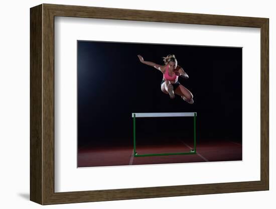 Determined Young Woman Athlete Jumping over a Hurdles-dotshock-Framed Photographic Print