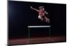 Determined Young Woman Athlete Jumping over a Hurdles-dotshock-Mounted Photographic Print