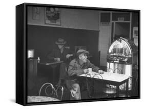 Dilapidated Shabby Man Sitting at the Table with a Cup of Coffee, Listening Dreamily to the Music-Peter Stackpole-Framed Stretched Canvas