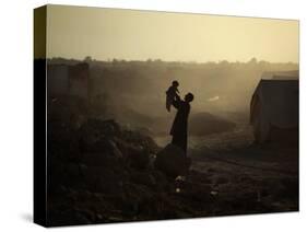 Displaced Man Holds His Baby Next to His Tent in Jalozai Refugee Camp Near Peshawar, Pakistan-null-Stretched Canvas
