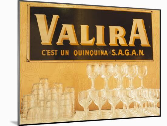 Empty Wine & Water Glasses in Front of Valira Publicity Sign-Peter Medilek-Mounted Photographic Print