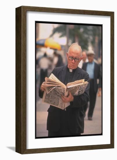 Episcopalian Priest Reading a Newspaper While Walking in Street, New York City-Vernon Merritt III-Framed Photographic Print