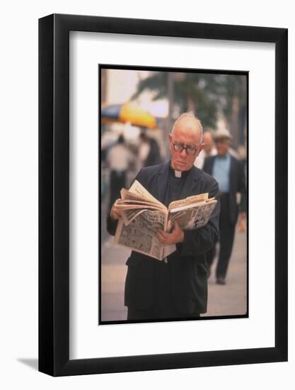 Episcopalian Priest Reading a Newspaper While Walking in Street, New York City-Vernon Merritt III-Framed Photographic Print