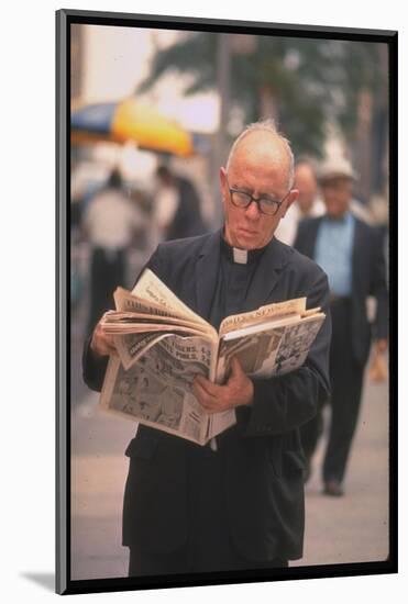 Episcopalian Priest Reading a Newspaper While Walking in Street, New York City-Vernon Merritt III-Mounted Photographic Print