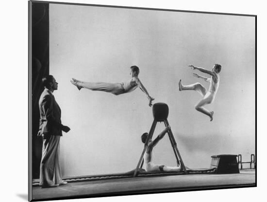 Erik Flensted Jensen, Coach of Danish Gymnastic Team, Watching as Three Men Perform-Gjon Mili-Mounted Photographic Print