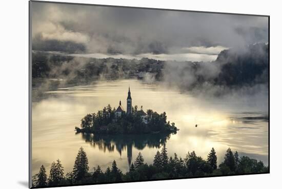 Europe, Slovenia, Bled - A Pletna Boat Arriving At The Island Of Lake Bled During A Foggy Sunrise-Aliaume Chapelle-Mounted Photographic Print