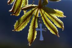 Pendant with cross on a young green chestnut leaf at springtime-null-Giclee Print