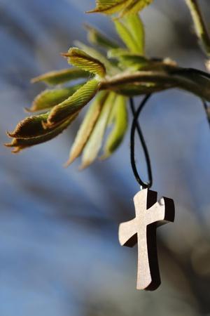 Pendant with cross on a young green chestnut leaf at springtime