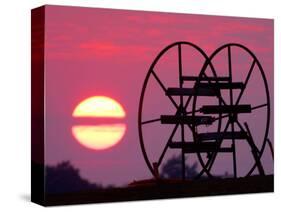 Farm Equipment is Silhouetted by a Setting Sun-null-Stretched Canvas