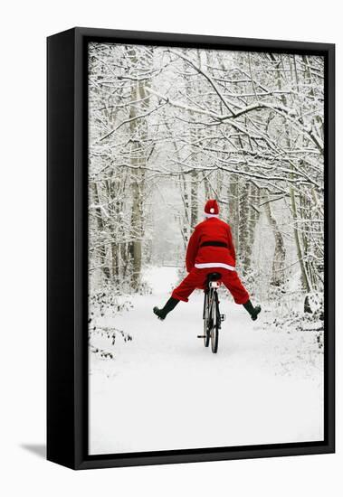 Father Christmas Riding Bicycle in Snowy Woodland Path-null-Framed Stretched Canvas