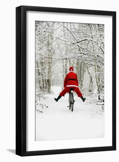 Father Christmas Riding Bicycle in Snowy Woodland Path-null-Framed Premium Photographic Print