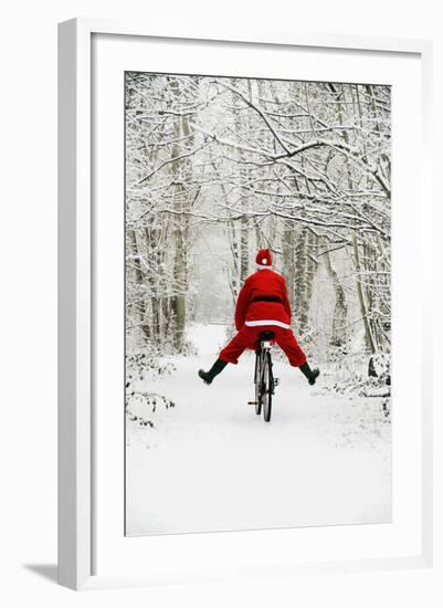 Father Christmas Riding Bicycle in Snowy Woodland Path-null-Framed Photographic Print