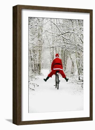 Father Christmas Riding Bicycle in Snowy Woodland Path-null-Framed Photographic Print