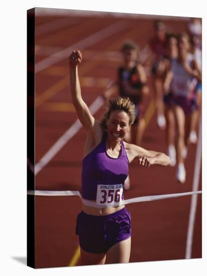 Female Runner Victorious at the Finish Line in a Track Race-null-Stretched Canvas