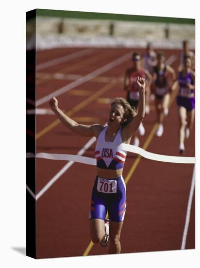 Female Runner Victorious at the Finish Line in a Track Race-null-Stretched Canvas