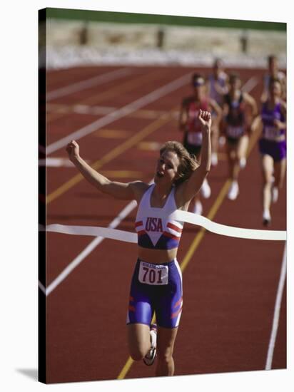 Female Runner Victorious at the Finish Line in a Track Race-null-Stretched Canvas