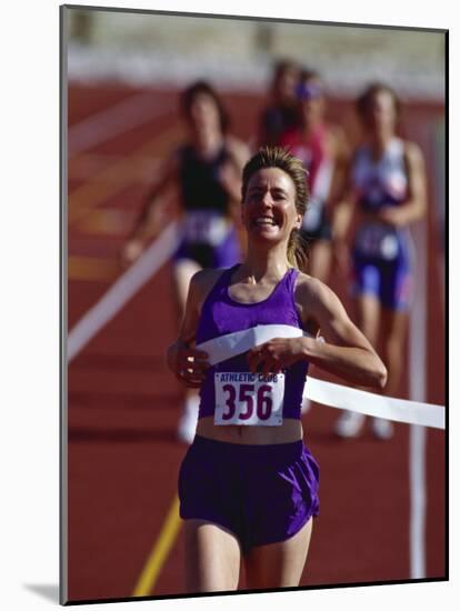 Female Runner Victorious at the Finish Line in a Track Race-null-Mounted Photographic Print