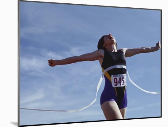 Female Runner Victorious at the Finish Line in a Track Race-null-Mounted Photographic Print