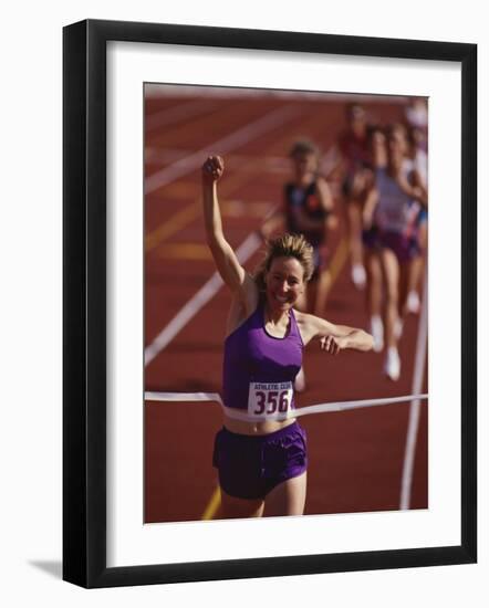 Female Runner Victorious at the Finish Line in a Track Race-null-Framed Photographic Print