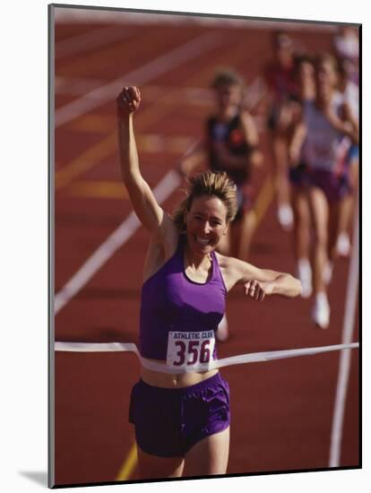 Female Runner Victorious at the Finish Line in a Track Race-null-Mounted Photographic Print