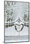 Fence line and fresh snow with trees line lane and metal gate with Christmas wreath.-Darrell Gulin-Mounted Photographic Print