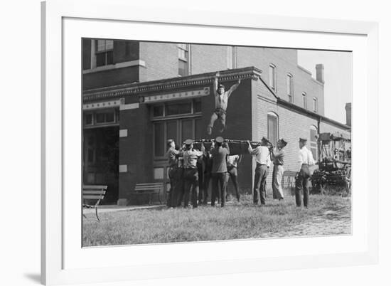 Firefighter Jumps Into Net Held By Fellow Firemen-null-Framed Art Print